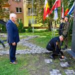 Prezydent Tadeusz Truskolaski w asyście strażnika miejskiego stoi przed pomnikiem  