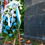 Biało-niebieskie kwiaty złożone pod pomnikiem 