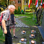 Mężczyzna oraz kobieta oddają cześć pod pomnikiem 