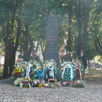 Warta honorowa stoi przy pomniku, pod którym znajdują się złożone kwiaty 