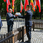 Zastępca prezydenta Zbigniew Nikitorowicz przekazuje światło pamięci strażnikowi miejskiemu