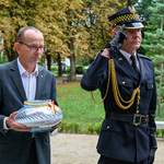 Zastępca prezydenta Zbigniew Nikitorowicz trzyma w dłoni światło pamięci, asystuje mu strażnik miejski