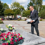 Zastępca prezydenta Zbigniew Nikitorowicz idzie położyć znicz na grobie poległych obrońców miasta