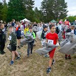 Dzieci podczas mistrzostw ploggingu trzymają w dłoniach szare worki na odpady zmieszane