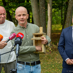 Pracownik Departamentu Ochrony Środowiska Jędrzej Grygoruk zabiera głos podczas konferencji prasowej trzymając w dłoniach drewnianą budkę lęgową