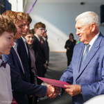 Uczeń w kręconych włosach odbiera gratulacje z rąk Prezydenta Tadeusza Truskolaskiego