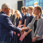 Uczennica w warkoczach odbiera gratulacje z rąk prezydenta Tadeusza Truskolaskiego 