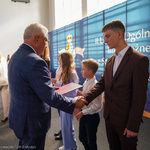Elegancko ubrany uczeń odbiera gratulacje z rąk prezydenta Tadeusza Truskolaskiego 