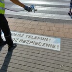 Na zdjęciu widać pracownika malującego napis na chodniku