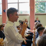 Uczeń przemawia podczas wydarzenia, w tle: uczniowie