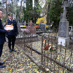 Zastępca prezydenta Rafał Rudnicki stoi nad grobem Wincentego Hermanowskiego trzymając w dłoniach znicz 