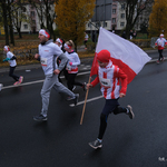 Uczestnik biegu trzyma w dłoniach Flagę Polski