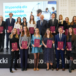Prezydent Tadeusz Truskolaski stoi w towarzystwie studentów trzymających w dłoniach teczki 