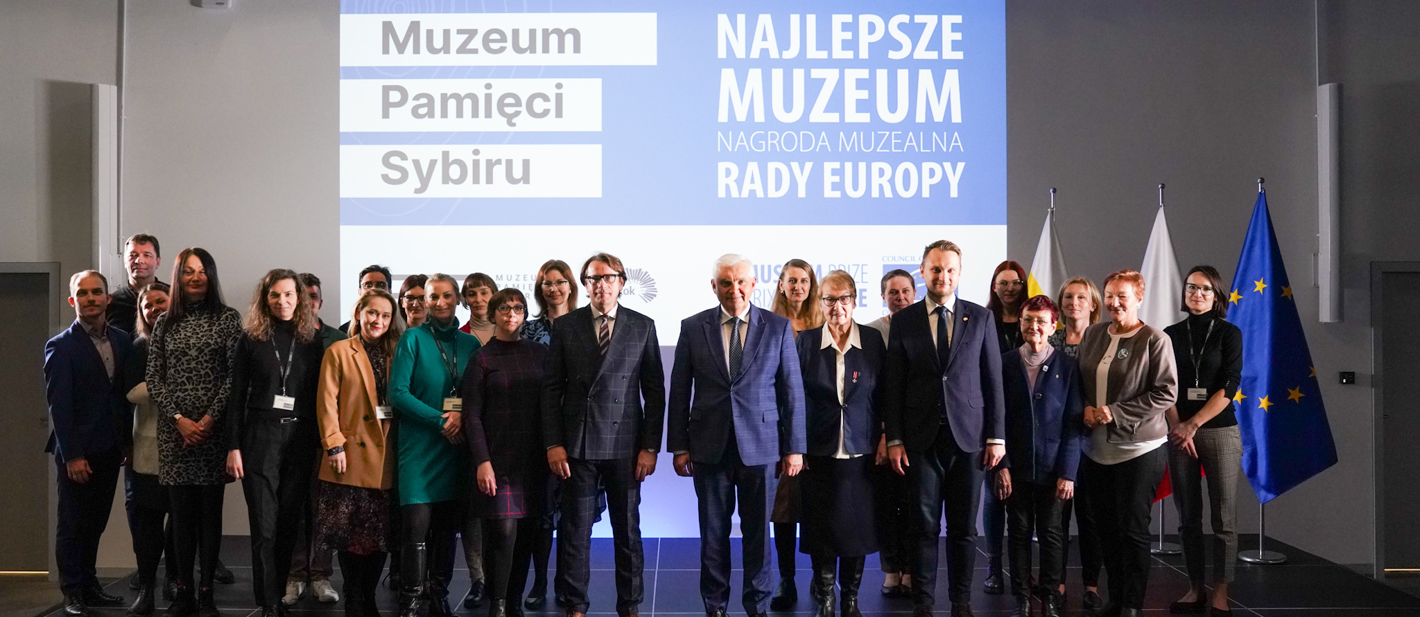 Uczestnicy konferencji prasowej, w tle napis: Muzeum Pamięci Sybiru, Najlepsze Muzeum, Nagroda Muzealna Rady Europy