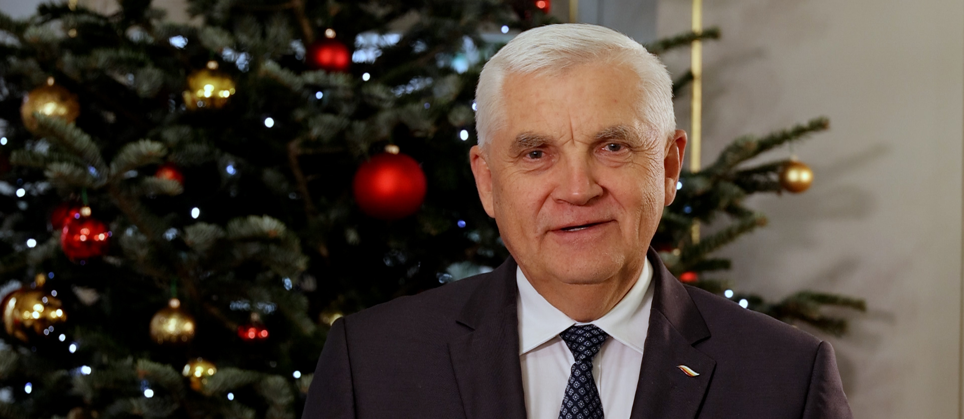 Prezydent Białegostoku Tadeusz Truskolaski na tle choinki świątecznej