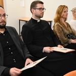 Dwóch mężczyzn oraz dwie kobiety siedzą na sali podczas uroczystości 