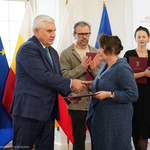 Starsza kobieta odbiera gratulacje z rąk prezydenta Tadeusza Truskolaskiego