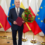 Mieczysław Mejsak trzyma w ręku list gratulacyjny i kwiaty 