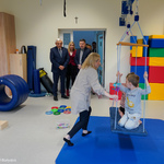 Prezydent Tadeusz Truskolaski podziwia salę zabaw, na której znajduje się dziecko bujające się na huśtawce 