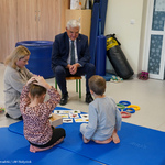 Prezydent Tadeusz Truskolaski rozmawia z chłopczykiem oraz dziewczynką siedzącymi na materacu 