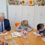 Prezydent Tadeusz Truskolaski oraz dwóch uczniów siedzą przy stole podczas prac plastycznych
