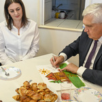 Prezydent Tadeusz Truskolaski podpisuje obrazek przedstawiający Dom pod modrzewiem
