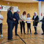 Prezydent Tadeusz Truskolaski oraz inni uczestnicy spotkania przecinają wstęgę otwierającą salę gimnastyczną 