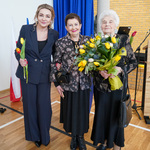 Trzy kobiety trzymają w dłoni kwiaty