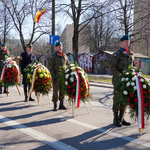Żołnierze trzymają w dłoniach wieńce kwiatowe