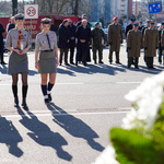 Trzy harcerki podążają w stronę pomnika trzymając w dłoni znicz