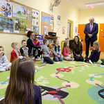 Prezydent Tadeusz Truskolaski rozmawia z dziećmi siedzącymi na dywanie w sali lekcyjnej