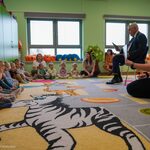 Prezydent Tadeusz Truskolaski siedzi na krześle, na dywanie siedzą dzieci