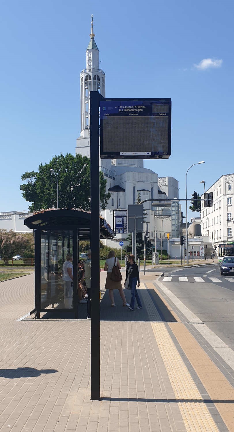 tablica informacji pasażerskiej na przystanku autobusowym w tle Kościół św. Rocha