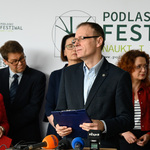Mężczyzna stoi w otoczeniu uczestników konferencji