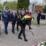 Zastępca prezydenta, Przemysław Tuchliński w towarzystwie dyrektora Muzeum Pamięci Sybiru Wojciecha Śleszyńskego i przedstawicieli służb mundurowych zmierza pod Pomnik -Grób Nieznanego Sybiraka. Przedstawiciel straży miejskiej niesie wieniec. W tle widać uczestników uroczystości 