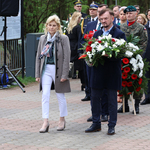 Mężczyzna niesie w ręku wieniec z kwiatów