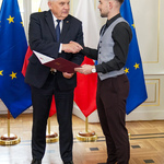 Prezydent Truskolaski ścika dloń młodemu mężczyźnie