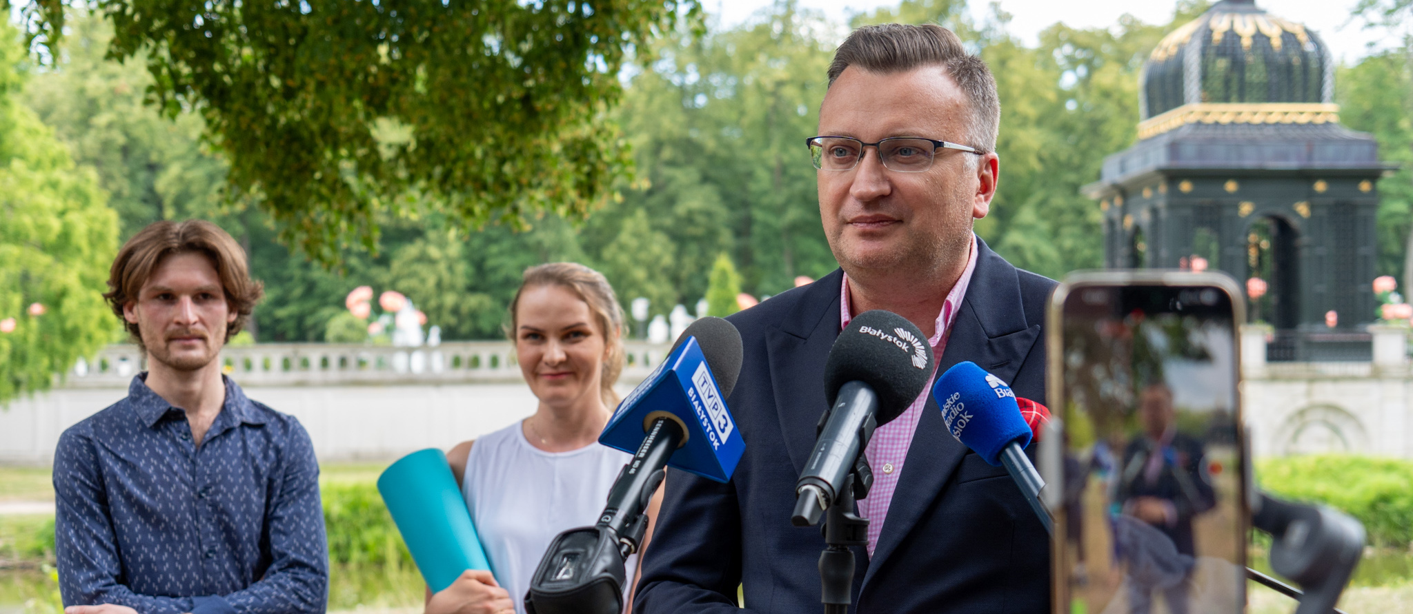 Zastępca Prezydenta Rafał Rudnicki udziela wywiadu do mikrofonów podczas konferencji, w tle joginka Anna Chomczyk