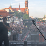 Kuba Szmajkowski śpiewa do mikrofonu, w tle białostoczanie zgromadzeni pod sceną