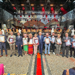 Trzynaście osób i jedna organizacja które otrzymały Honorowe Wyróżnienie Prezydenta Miasta Białegostoku „Urbi Meritus – Zasłużony Miastu” stoją pod scena z Prezydentem Tadeuszem Truskolaskim