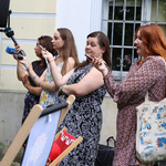 Dziennikarki stoją z mikrofonami i dyktafonami podczas konferencji
