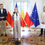 Aleksandra Pietruk mówi do mikrofonu podczas spotkania, w tle stoi zastępca prezydenta Rafał Rudnicki oraz trener Paweł Pietruk