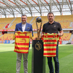 Zastępca prezydenta Rafał Rudnicki oraz prezes Jagiellonii Wojciech Pertkiewicz trzymają nowe koszulki reprezentacji, po środku stoi puchar Mistrza Polski