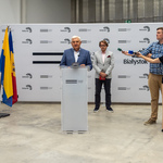 Prezydent Tadeusz Truskolaski stoi przy mównicy podczas konferencji, obok stoją reporterzy