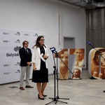Rzecznik prasowy Urszula Boublej przemawia do mikrofonu podczas konferencji, w tle fragment wystawy i inni uczestnicy