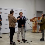 Prof. dr hab. Wojciech Śleszyński mówi do mikrofonów podczas konferencji, obok stoją dziennikarze