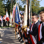 Uczniowie stoją w szeregu ze sztandarami 