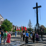 Uczestnicy uroczystości stoją wokół pomnika w kształcie krzyża 