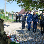 Zastępca prezydenta stoi w towarzystwie mundurowych przed pomnikiem