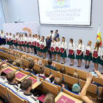 Uczennice ubrane jednakowo w białe bluzki i granatowe spódniczki trzymają w rękach wręczone stypendia, po środku stoi prezydent Tadeusz Truskolaski 